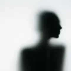 En suddig syn på morgonen. Silhuetten av en person, sedd i profil, framträder genom ett frostat glas.