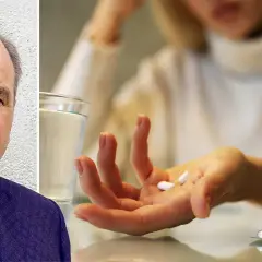 En man med bekymrat ansikte bredvid en hand som håller tabletter, kanske för att lindra migrän. Naproxen mot migrän kan vara en lösning.