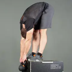 Man utför en jefferson curl med kettlebell, stående på en box.