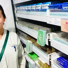 En farmaceutstudent vid en apotekshylla med smärtlindrande mediciner. Frågor om naproxen 500 mg hur ofta kan besvaras här.