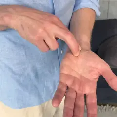 En man pekar på sin handled, kanske för att visa var han känner ont i nacken och domningar i fingrarna.