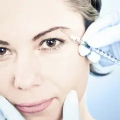 En kvinna får en injektion med botulinumtoxin, även känt som botox, i pannan för att släta ut rynkor.