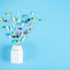 En vit burk med piller som sprids ut. Frågan om är Alvedon antiinflammatorisk är relevant för dessa mediciner.