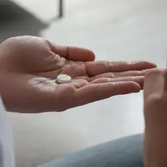 En hand håller en tablett, en annan ett glas vatten. Antidepressiva kan hjälpa mot nedstämdhet och ångest.
