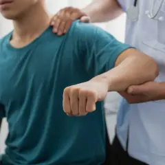 Läkare undersöker en patient med misstänkt armbåge ur led.