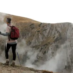 Vandrare med stavar, redo att utforska bergsterräng med moln som sveper in. Stavgång teknik är nyckeln för att navigera i denna utmanande miljö.