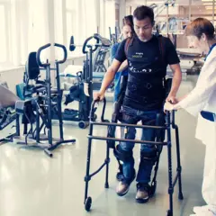 Man med gånghjälpmedel och stöd av terapeut, rehabiliterar efter neglekt stroke.