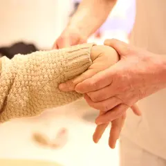 En person undersöker en arm med stickad tröja, möjligen för att bedöma ehlers danlos syndrom symtom som överrörlighet.