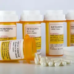 Flera medicinburkar med starka läkemedel som morfin, fentanyl och oxykodon. En burk med oxykodon ligger ner med kapslar utspridda. Dessa är exempel på snabbverkande morfin och liknande preparat.