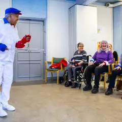 Man i vit dräkt leder en grupp äldre i en Ronnie Gardiner Method-övning.
