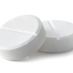 Two white, round pills with a score line down the middle, on a white background.