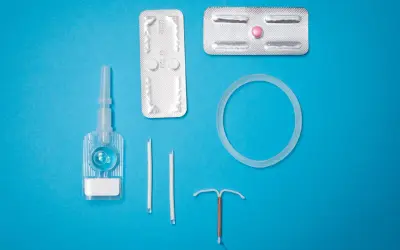 Various birth control methods including IUDs, pills, and a vaginal ring on a blue background.
