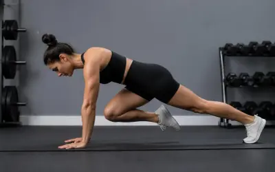 Kvinna utför mountain climbers på en träningsmatta i ett gym.