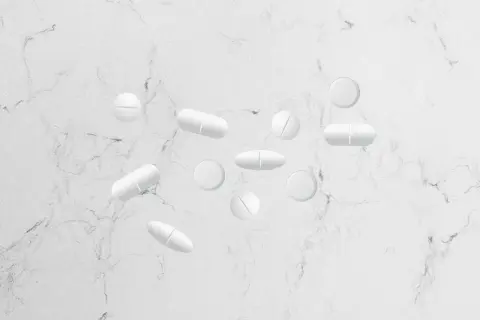 Flera vita tabletter, som gabapentin och alvedon, ligger utspridda på en marmorerad yta.