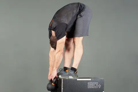Man utför en jefferson curl med kettlebell, stående på en box.