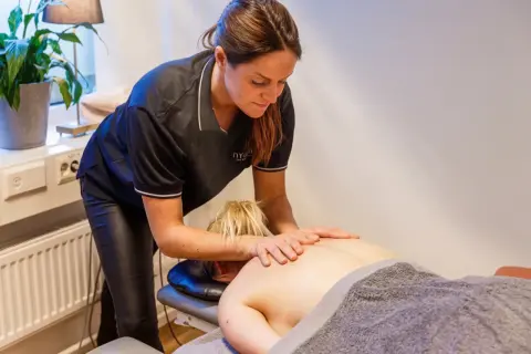 En massör utför ryggmassage, en av många olika typer av massage som erbjuds för avslappning och välbefinnande.