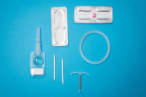 Various birth control methods including IUDs, pills, and a vaginal ring on a blue background.
