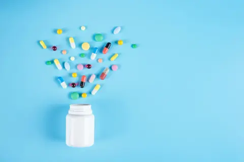 En vit burk med piller som sprids ut. Frågan om är Alvedon antiinflammatorisk är relevant för dessa mediciner.