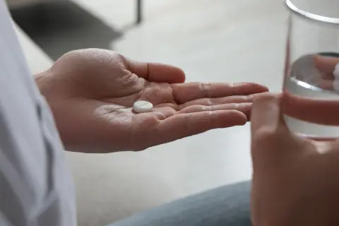 En hand håller en tablett, en annan ett glas vatten. Antidepressiva kan hjälpa mot nedstämdhet och ångest.