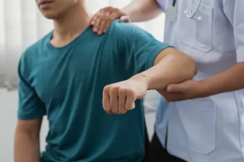 Läkare undersöker en patient med misstänkt armbåge ur led.