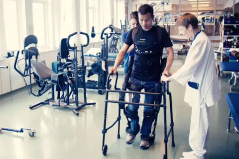 Man med gånghjälpmedel och stöd av terapeut, rehabiliterar efter neglekt stroke.