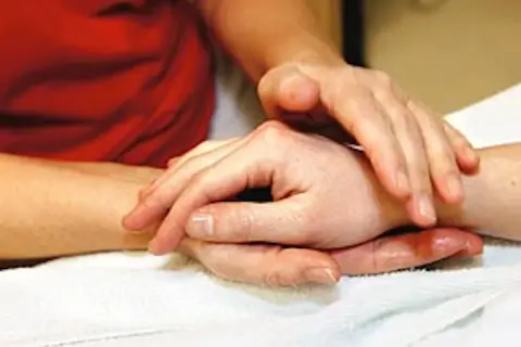 Händer som utför taktil massage på en arm. En varm och lugnande beröring.
