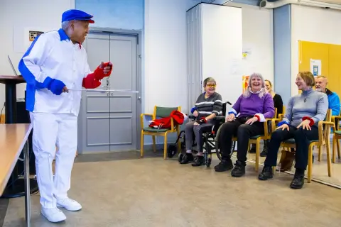 Man i vit dräkt leder en grupp äldre i en Ronnie Gardiner Method-övning.