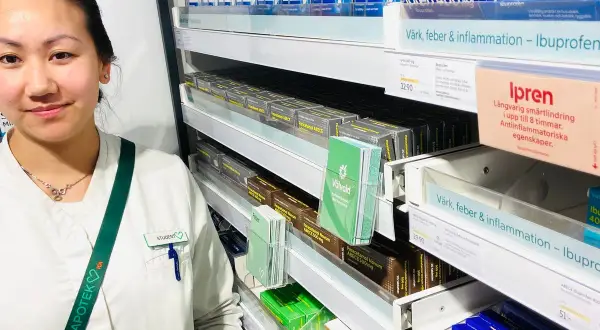 En farmaceutstudent vid en apotekshylla med smärtlindrande mediciner. Frågor om naproxen 500 mg hur ofta kan besvaras här.