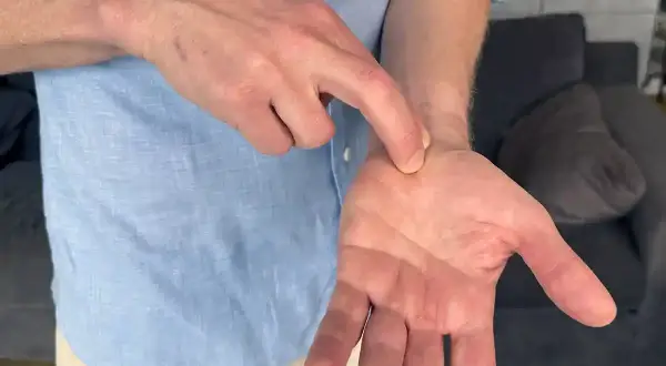 En man pekar på sin handled, kanske för att visa var han känner ont i nacken och domningar i fingrarna.