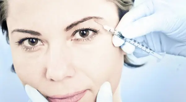 En kvinna får en injektion med botulinumtoxin, även känt som botox, i pannan för att släta ut rynkor.