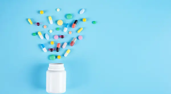 En vit burk med piller som sprids ut. Frågan om är Alvedon antiinflammatorisk är relevant för dessa mediciner.