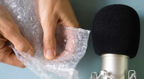 Händer som försiktigt knäpper bubbelplast nära en mikrofon, skapar härliga asmr ljud.