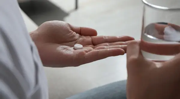 En hand håller en tablett, en annan ett glas vatten. Antidepressiva kan hjälpa mot nedstämdhet och ångest.