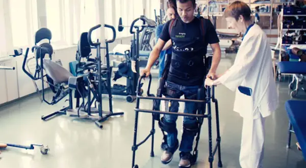 Man med gånghjälpmedel och stöd av terapeut, rehabiliterar efter neglekt stroke.