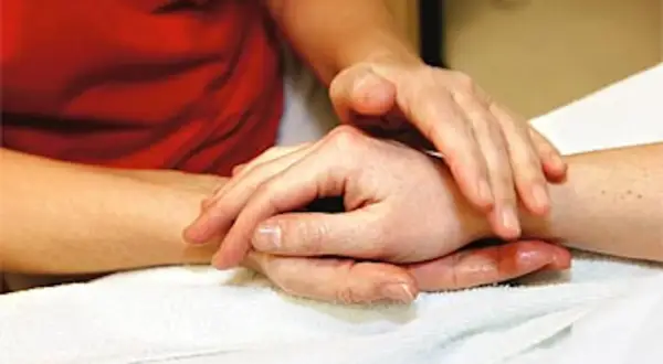 Händer som utför taktil massage på en arm. En varm och lugnande beröring.