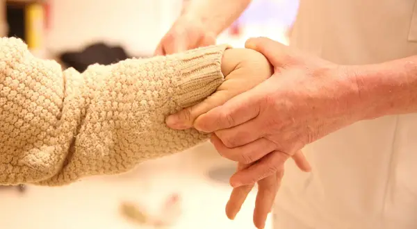En person undersöker en arm med stickad tröja, möjligen för att bedöma ehlers danlos syndrom symtom som överrörlighet.