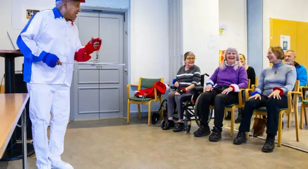 Man i vit dräkt leder en grupp äldre i en Ronnie Gardiner Method-övning.