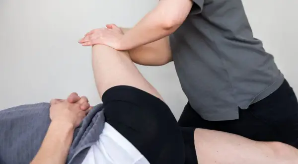 Fysioterapeut behandlar en person som har ont i låret framsida.