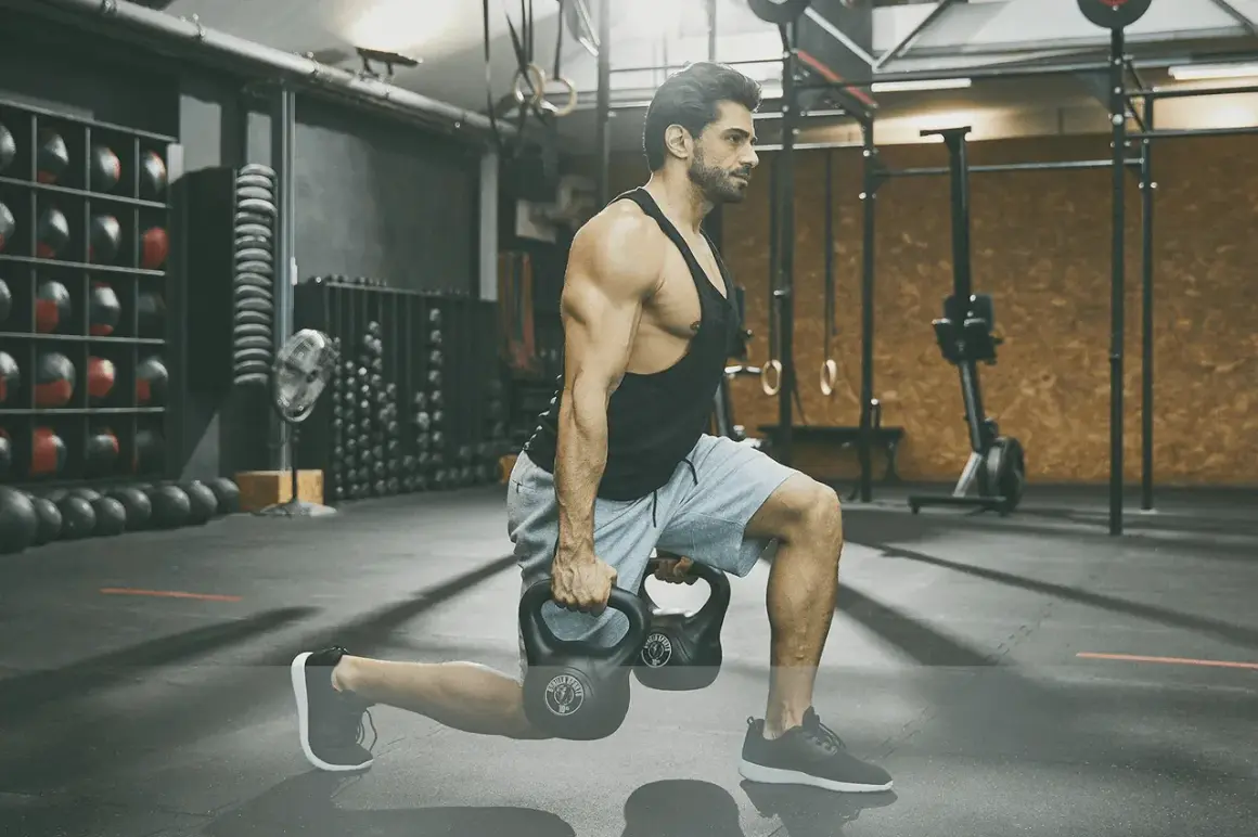 Man utför utfall med kettlebells under ett intensivt crossfit pass i ett modernt gym.