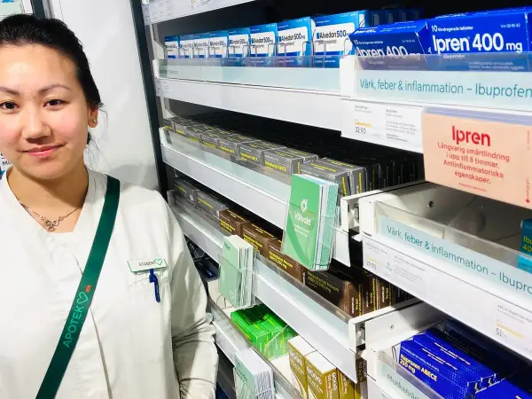 En farmaceutstudent vid en apotekshylla med smärtlindrande mediciner. Frågor om naproxen 500 mg hur ofta kan besvaras här.
