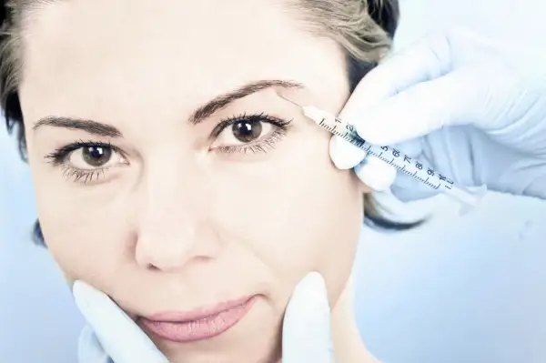 En kvinna får en injektion med botulinumtoxin, även känt som botox, i pannan för att släta ut rynkor.