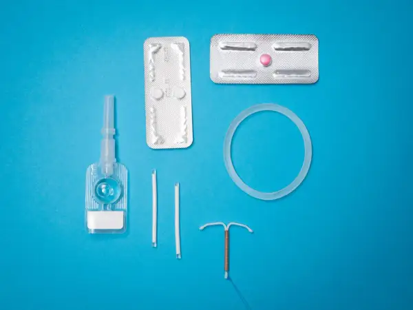 Various birth control methods including IUDs, pills, and a vaginal ring on a blue background.