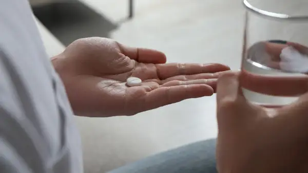 En hand håller en tablett, en annan ett glas vatten. Antidepressiva kan hjälpa mot nedstämdhet och ångest.