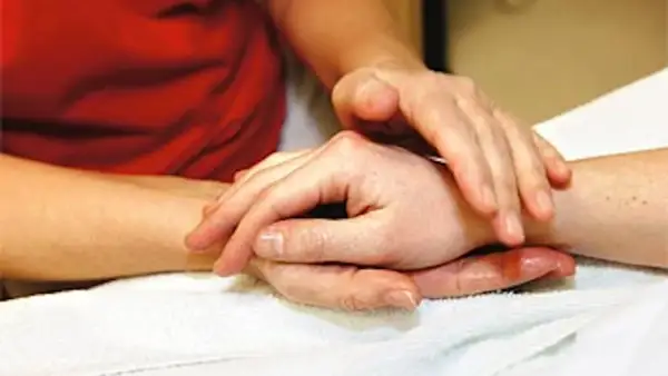 Händer som utför taktil massage på en arm. En varm och lugnande beröring.
