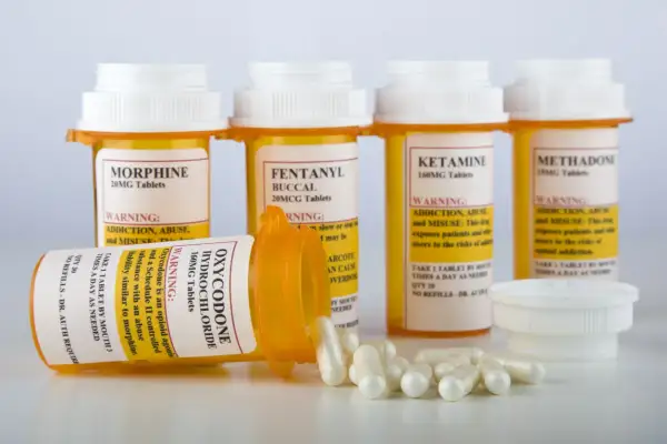 Flera medicinburkar med starka läkemedel som morfin, fentanyl och oxykodon. En burk med oxykodon ligger ner med kapslar utspridda. Dessa är exempel på snabbverkande morfin och liknande preparat.